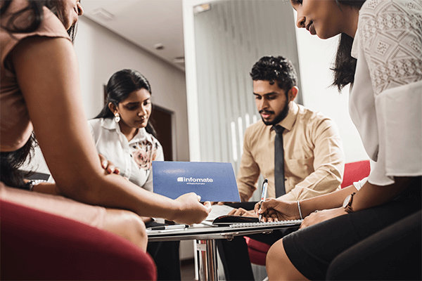 Team members holding an official Infomate folder and discussing business process outsourcing services during a client consultation in Colombo.