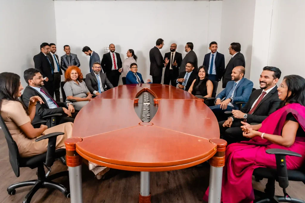 Corporate team members networking and collaborating around a large boardroom table at Infomate, a leading BPO company in Sri Lanka.