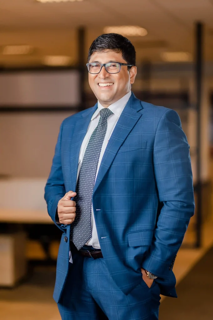 Senior business leader in a formal blue suit, representing corporate leadership and professional business process outsourcing services at Infomate.